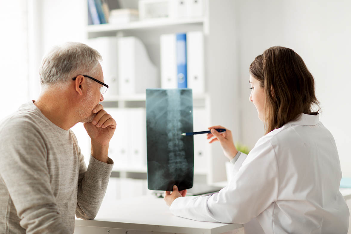 medicine, healthcare, surgery, radiology and people concept - doctor showing x-ray of spine to senior man at hospital